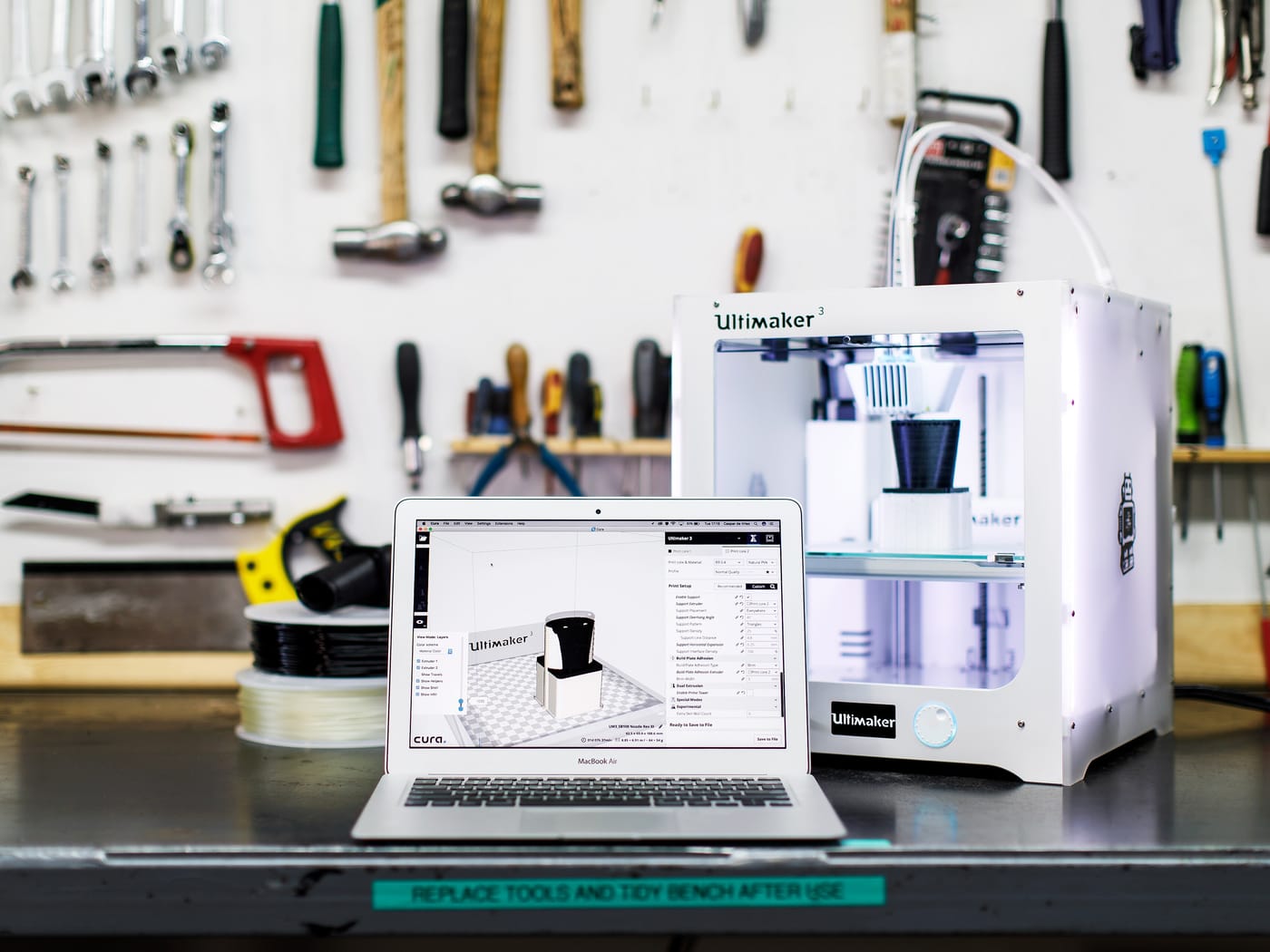 A 3D printer running a part with the model open in slicing software